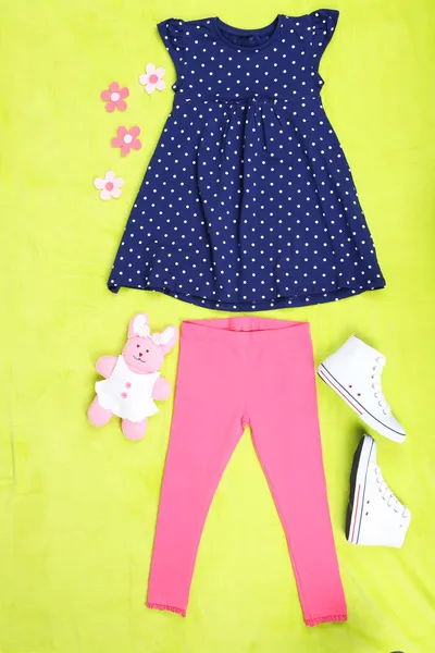 Schöne Kleidung für kleines Mädchen auf grünem Hintergrund — Stockfoto