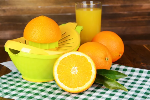Citrus press and oranges on table on wooden background — Stock Photo, Image