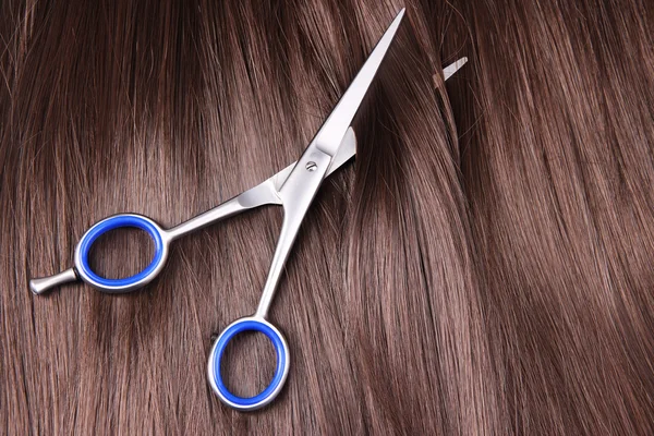 Long brown hair with scissors on close up — Stock Photo, Image