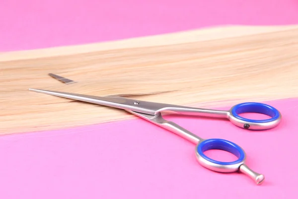 Lunghi capelli biondi con forbici su sfondo rosa — Foto Stock