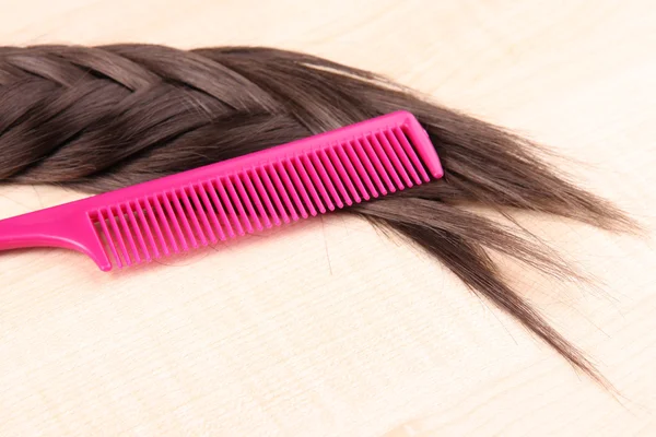 Cabello castaño largo con peine sobre fondo de madera —  Fotos de Stock