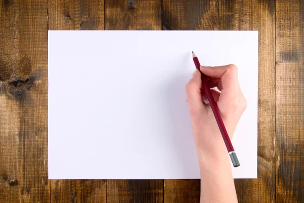 Kalem ve Kağıt ahşap arka plan üzerinde tutan el — Stok fotoğraf