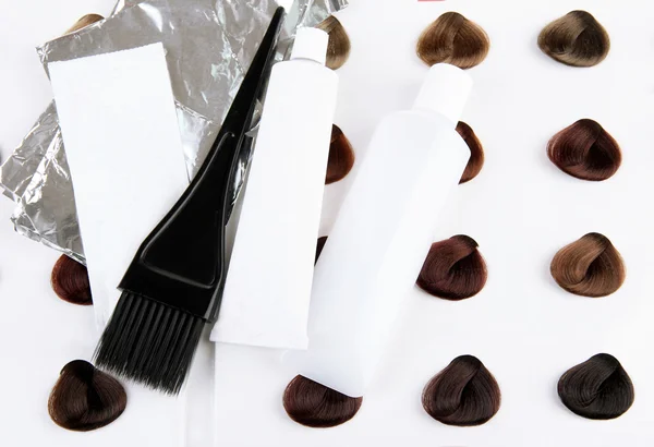 Kit de tintura de cabelo a bordo com amostras de cabelo de diferentes cores de fundo — Fotografia de Stock