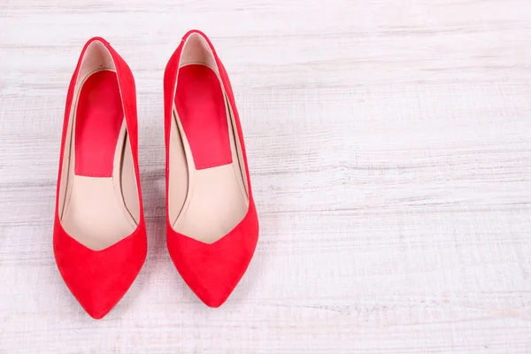 Hermosos zapatos femeninos rojos, sobre fondo de madera — Foto de Stock