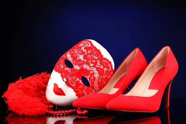 Sapatos femininos vermelhos bonitos e máscara de carnaval, no fundo azul — Fotografia de Stock
