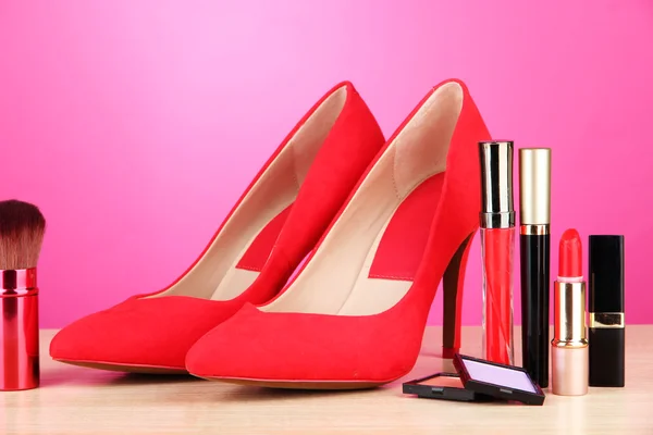 Beautiful red female shoes with cosmetics, on pink background — Stock Photo, Image