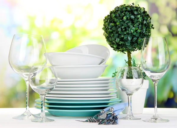 Sauberes Geschirr auf dem Tisch vor natürlichem Hintergrund — Stockfoto