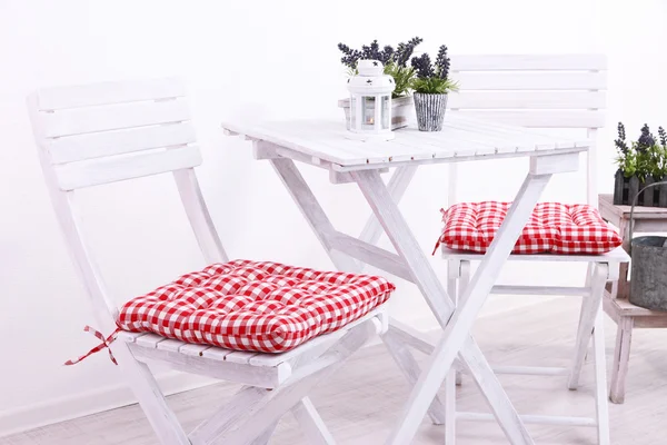 Sedie da giardino e tavolo con fiori su basamento in legno su sfondo bianco — Foto Stock