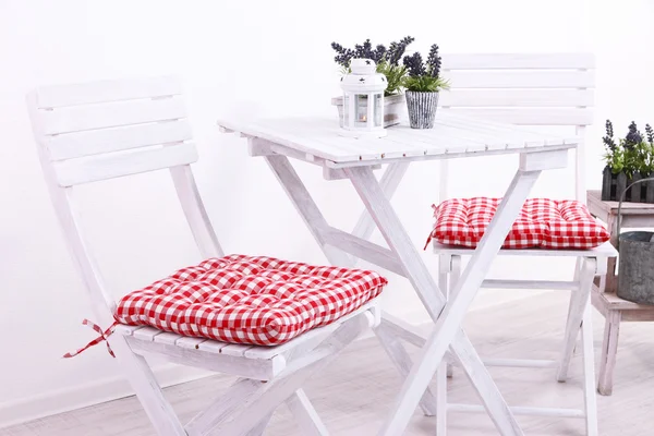 Cadeiras de jardim e mesa com flores em suporte de madeira sobre fundo branco — Fotografia de Stock