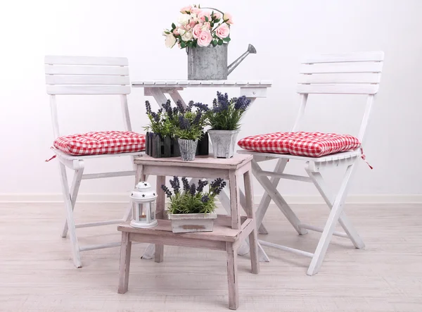 Стулья и стол с цветами на деревянном фоне — стоковое фото