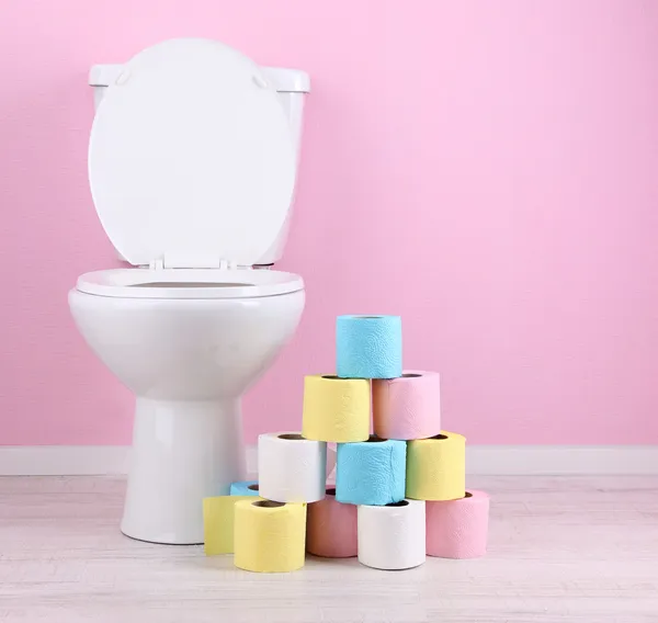 Weiße Toilettenschüssel und bunte Rollen Toilettenpapier im Badezimmer — Stockfoto