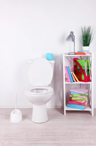 WC bianco ciotola e stand con libri, su sfondo parete a colori — Foto Stock