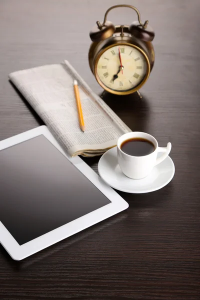 Tableta, periódico, taza de café y despertador en mesa de madera —  Fotos de Stock