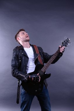 genç müzisyen gitar çalıyor ve şarkı söyleme, koyu renk arka plan üzerinde