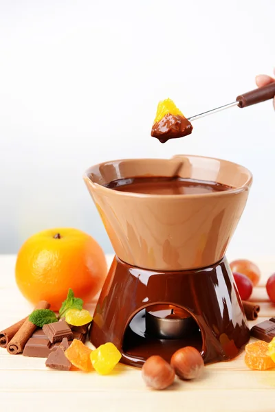 Chocolade fondue met fruit, op houten tafel, op lichte achtergrond — Stockfoto