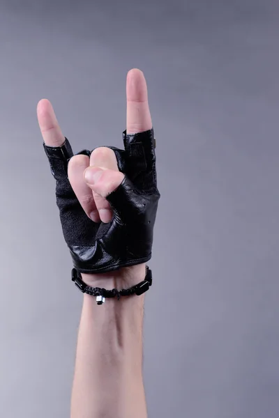 Hand of rocker in bracelet and leather mitten, on gray background — Stock Photo, Image