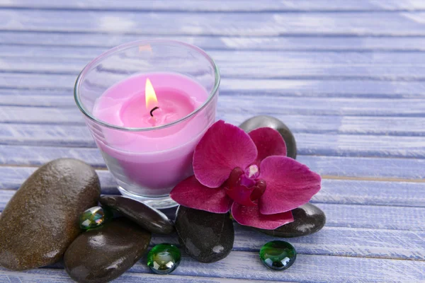 Beautiful colorful candles and orchid flower,on color wooden background — Stock Photo, Image