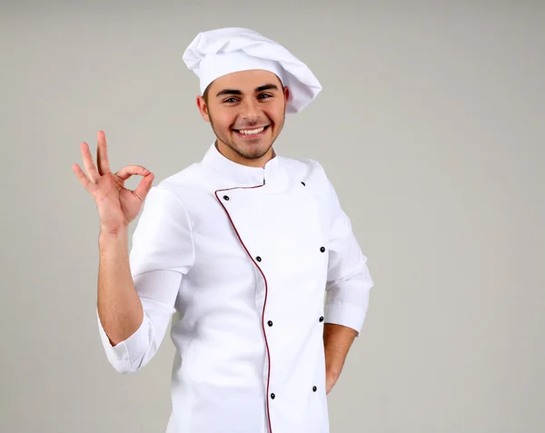 Professionell kock i vit uniform och hatt, på grå bakgrund — Stockfoto