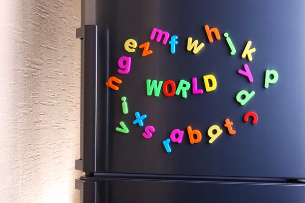 Word World deletreado usando letras magnéticas de colores en el refrigerador —  Fotos de Stock