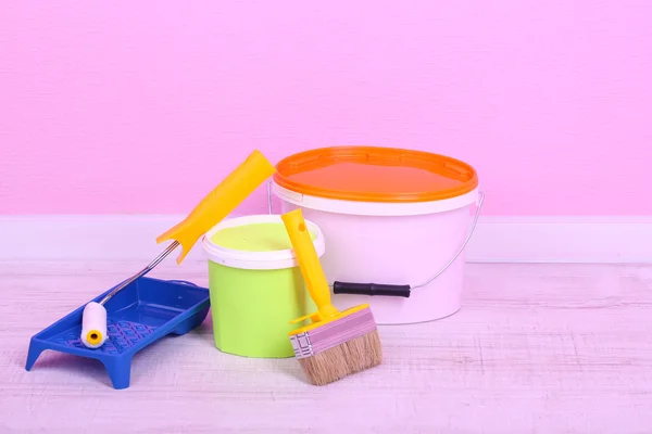 Tintas, rolo e pincel no chão no quarto no fundo da parede — Fotografia de Stock