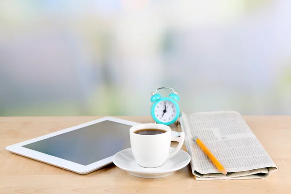 Tableta, periódico, taza de café y despertador en mesa de madera —  Fotos de Stock