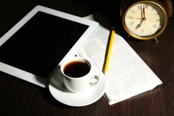 Tabletki, gazety, filiżankę kawy i budzik na drewnianym stole — Zdjęcie stockowe