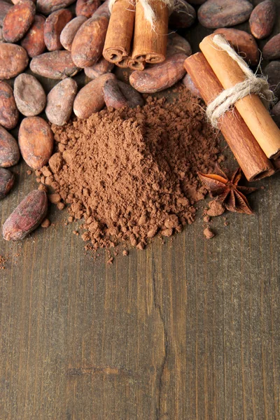 Fèves de cacao, poudre de cacao et épices sur fond de bois — Photo