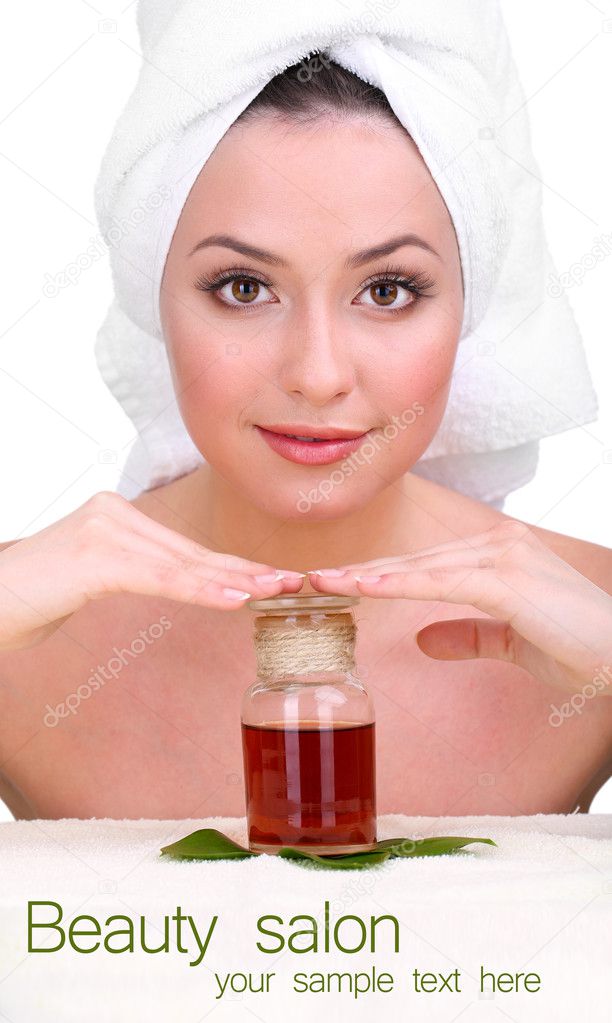 Beautiful young woman with towel on her head and oil bottle isolated on white