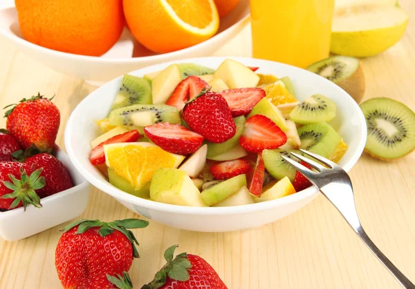 Nützlicher Obstsalat aus frischen Früchten und Beeren in Schüssel auf Holztisch in Großaufnahme — Stockfoto