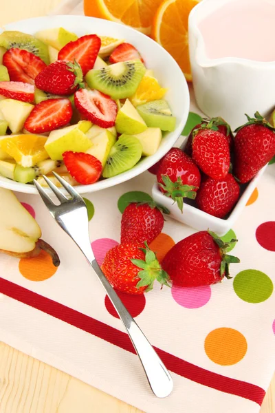 Корисний фруктовий салат зі свіжих фруктів і ягід в мисці на серветці на дерев'яному столі крупним планом — стокове фото