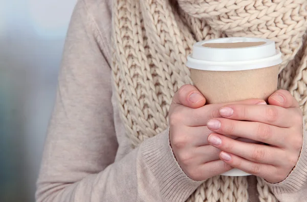 Bebida caliente en taza de papel en las manos sobre fondo brillante — Foto de Stock