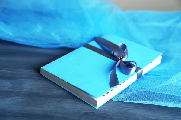Buch mit Farbband umwickelt, auf Holztisch auf dunklem Hintergrund — Stockfoto