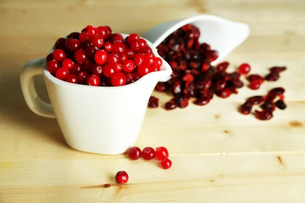 Fresh and dry cranberry in pitchers on wooden table close-up — Stock Photo, Image