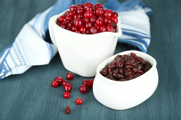 Fresh and dry cranberry in pitchers and bowl on wooden table close-up — Stock Photo, Image