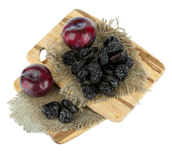 Ameixas frescas e secas em tábua de madeira, isoladas a branco — Fotografia de Stock