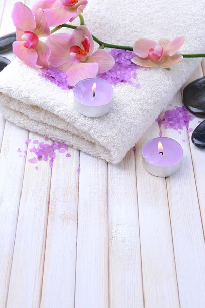 Stilleben med vackra blommande orkidé blomma, handduk och skål med havssalt, på färg trä bakgrund — Stockfoto