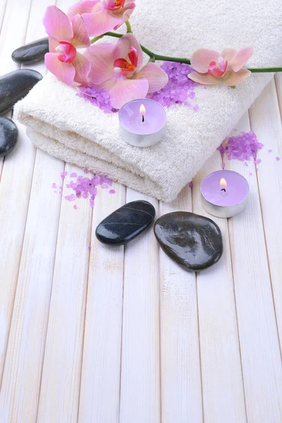 Still life with beautiful blooming orchid flower, towel and bowl with sea salt, on color wooden background — Stock Photo, Image