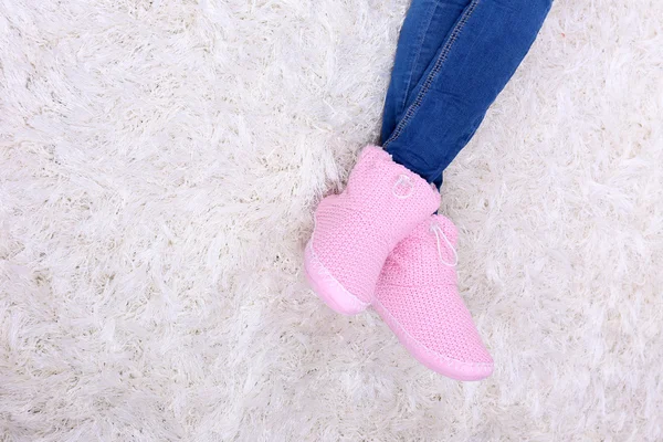 Piernas femeninas en pantalones vaqueros azules y zapatos de invierno para el hogar, sobre fondo de alfombra blanca —  Fotos de Stock