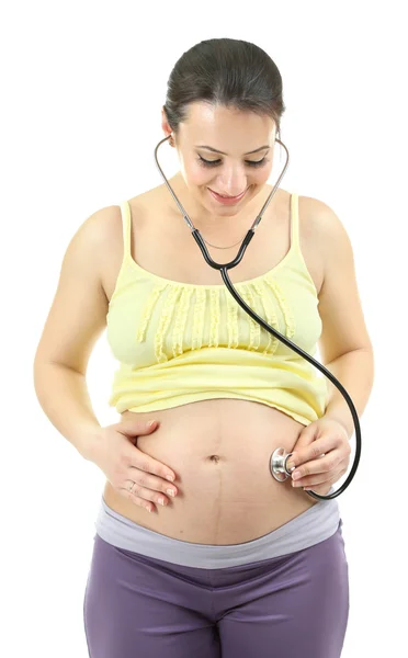 Young pregnant woman with stethoscope listening baby isolated on white — Stock Photo, Image