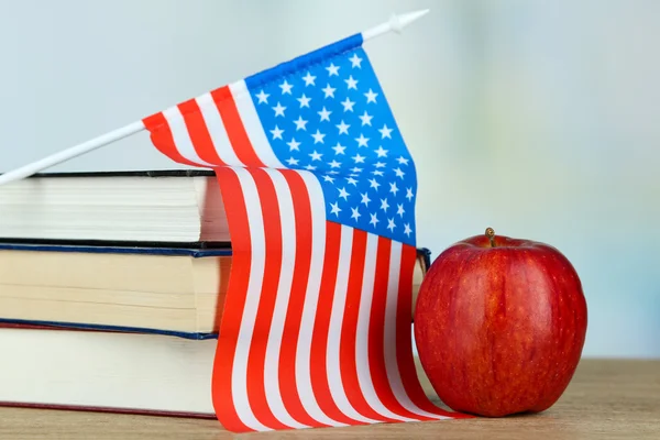 Composição da bandeira americana, livros e maçã na mesa de madeira, no fundo claro — Fotografia de Stock