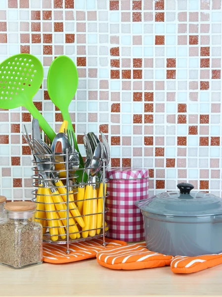 Dishes and cutlery in kitchen on table on mosaic tiles background — Stock Photo, Image