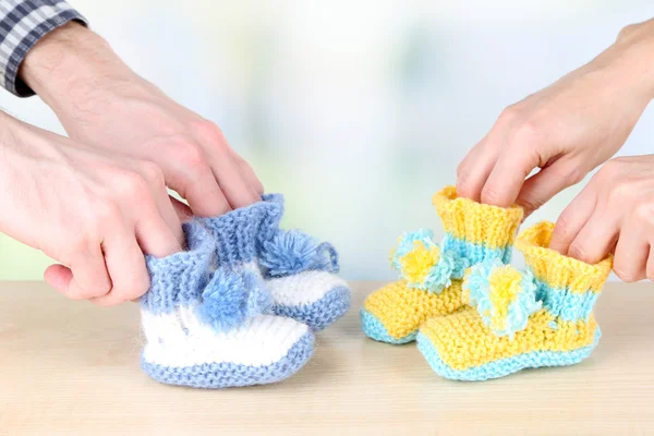 Mãos com botas de malha para bebê, no fundo claro — Fotografia de Stock