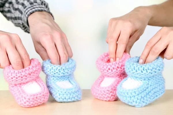 Hands with crocheted booties for baby, on light background — Stock Photo, Image