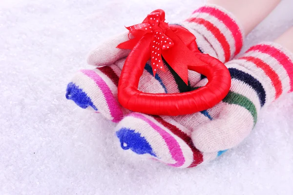 Female hands in mittens with heart on snow background — Stock Photo, Image