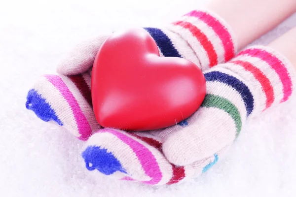 Manos femeninas en manoplas con corazón sobre fondo de nieve —  Fotos de Stock