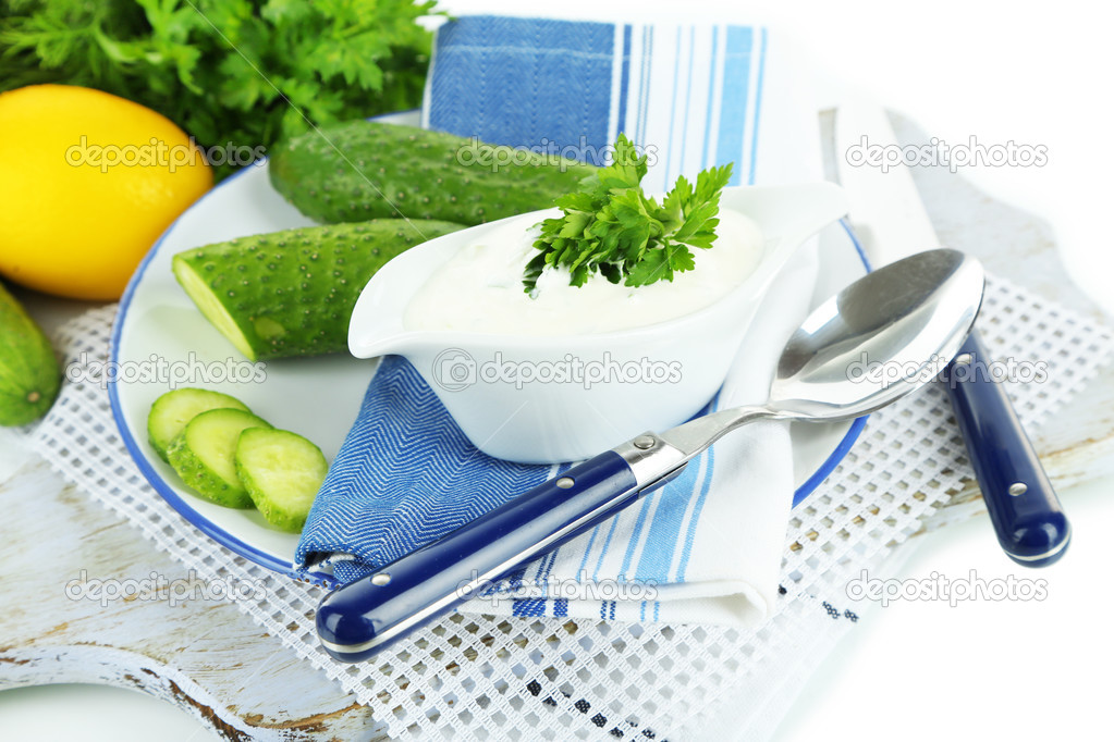 Cucumber yogurt in sauceboat, on color napkin, isolated on white