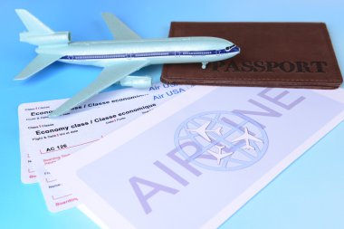 Açık mavi arka planda pasaportlu uçak biletleri.