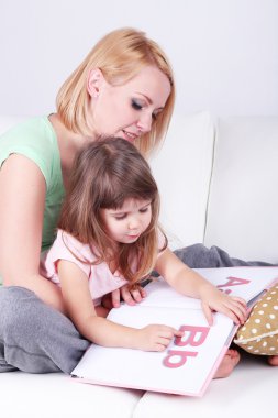sevimli küçük kız anne üzerinde gri arka koltukta ile kitap okuma