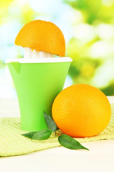 Citrus press, glass of juice and ripe oranges on white wooden table — Stock Photo, Image