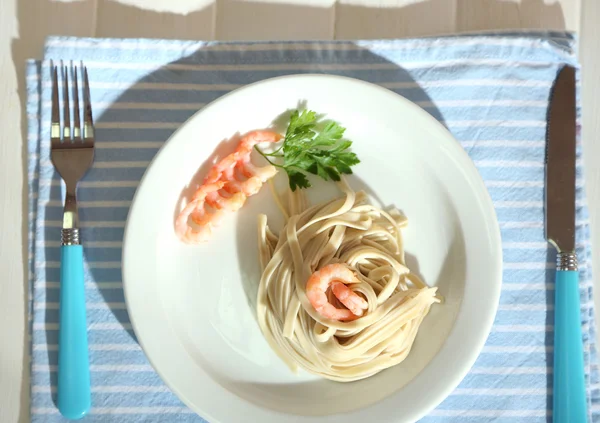 Těstoviny s krevetami na bílém štítku, na dřevěné pozadí — Stock fotografie